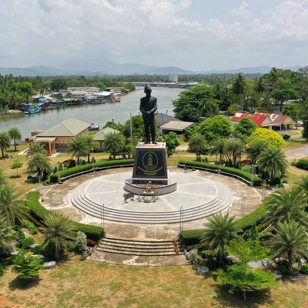 Ortasında erkek heykeli, arkasında nehir olan küçük bir kare.