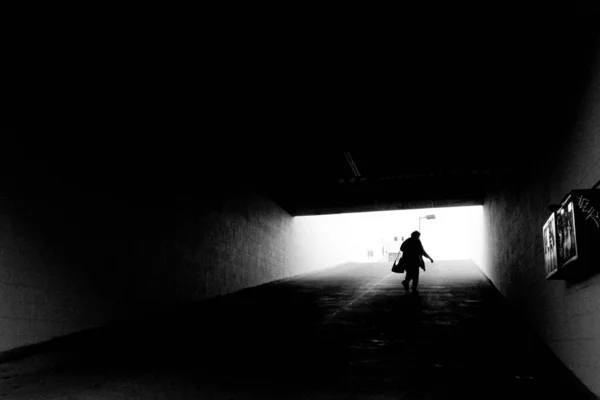 Graustufenaufnahme Einer Person Die Einem Tunnel Mit Einer Lichtquelle Auf — Stockfoto