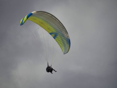 Gökyüzünde bulutların arka planında uçan renkli bir paraglider görüntüsü