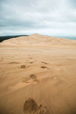 Gündüz vakti bulutlu gökyüzüne karşı kumdaki ayak izlerinin görüntüsü