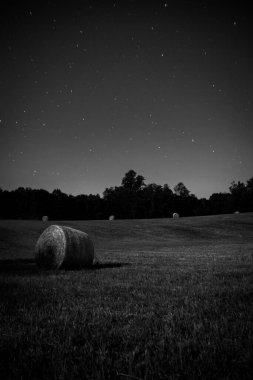 Geceleyin parlak gökyüzü arka planında saman balyasının dikey görüntüsü