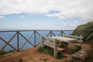 Tahta bir masa ve Atlantik Okyanusu manzaralı sandalyeler.