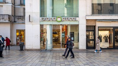 Büyük Optik Optisyen Dükkanı 'nın önünde logo ve tabela ile yürüyen bazı insanlar var..