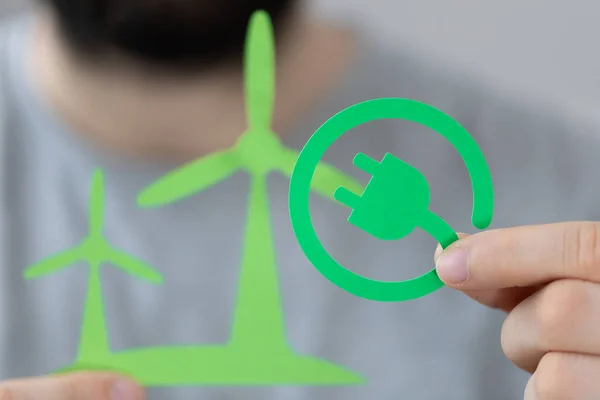 風力タービンに対して緑色の電気プラグアイコンを持つ男 — ストック写真