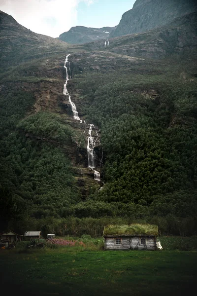 一座美丽的瀑布从靠近一座乡村小屋的山上滑落而下 — 图库照片