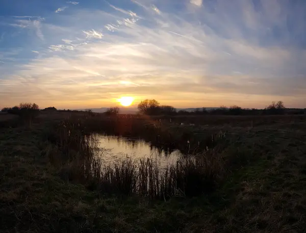 湖のある畑の上に美しい明るい夕日 — ストック写真