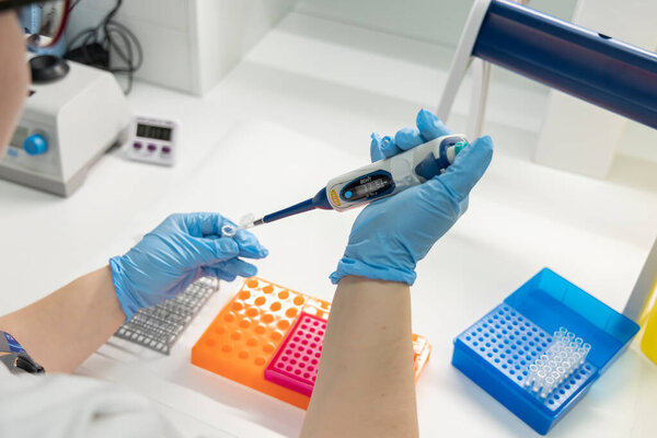 A laboratory technician working with medical equipment wearing blue nitrile gloves