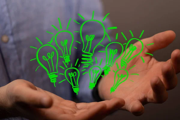 The 3d rendered green light bulbs floating in the air above the hands of a person