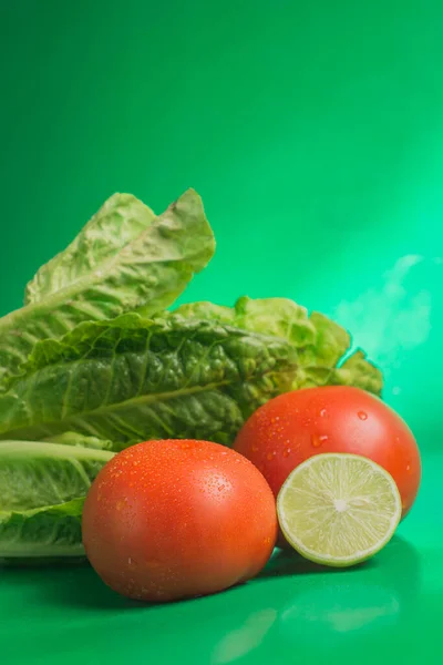 Primo Piano Lattuga Verde Fresca Pomodori Lime Uno Sfondo Verde — Foto Stock