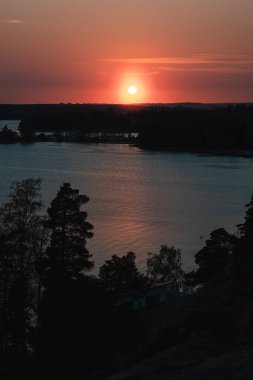 Arka planda renkli bir gökyüzü olan deniz kenarında gün batımının dikey görüntüsü.