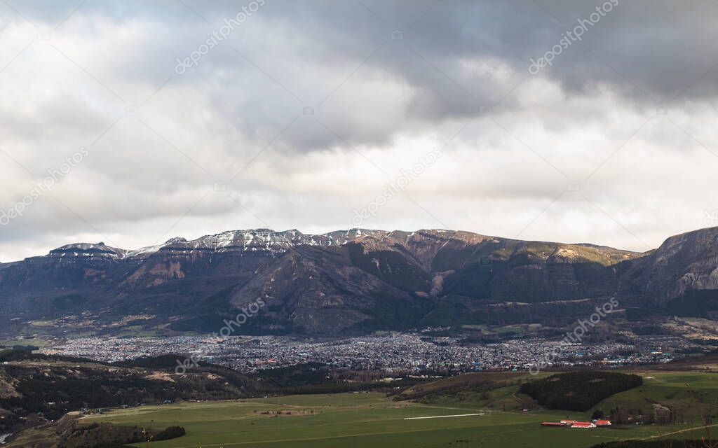 A photo of a landscape showing a mountain, a land, and a cloudy sky