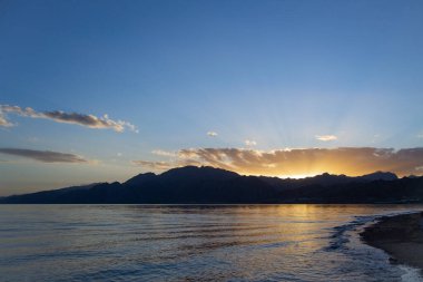 Gün batımında adası olan güzel bir deniz manzarası.