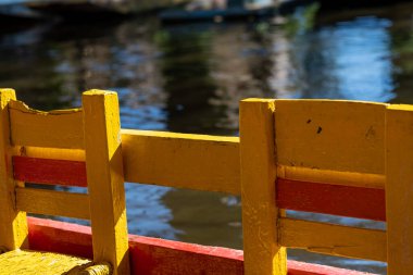 Mexico City 'deki Xochimilco kanallarında seyahat eden trajinera teknelerinin ayırt edici sarı sandalyeleri.