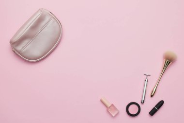 Pembe arka planda izole edilmiş bir çanta ve makyaj aleti