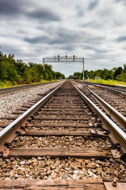 Bulutlu gökyüzüne karşı rayların üzerinde sinyal olan bir tren yolu.