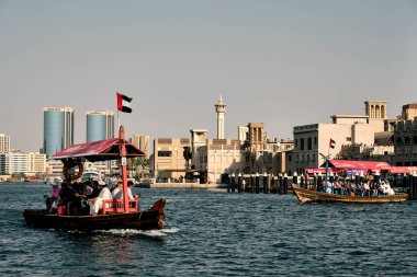 Bir grup turist Dubai Deresi 'nden geçen bir Abra teknesine biniyor.