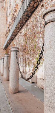 Eski bir binaya zincirle bağlanmış kısa kolonlardan oluşan dikey bir çekim.