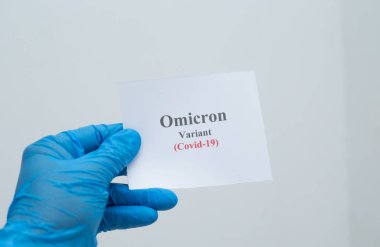 Lateks eldiven takan ve elinde COVID omicron varyantı olan birinin yakın çekimi.