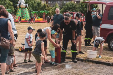 Bir çocuk ve itfaiyeci, Stare Zegrze bölgesinde bir itfaiye etkinliği sırasında suyla ateş ediyorlar.