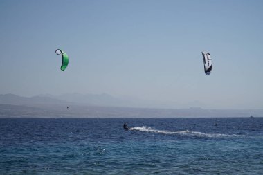 İsrail 'in Eilat denizinde rüzgar sörfü. Ürdün' ün Akabe kenti arka planda.