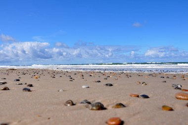Güzel bir kum ve mavi gökyüzünün altında renkli çakıl taşları.