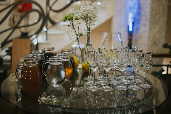 コップとドリンクの入った美しいガラスのテーブルのクローズアップショット屋内 — ストック写真
