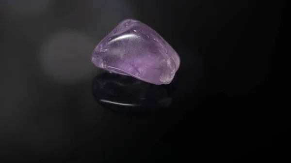 Una Piedra Amatista Púrpura Pastel Pulido Sobre Una Superficie Negra — Foto de Stock
