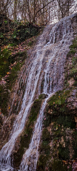 A vertical shot of a small waterfall flowing over the rocks