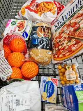Portakal, zeytin, pizza, tereyağı ve süt gibi Alman ürünleriyle dolu bir alışveriş arabasının üst görüntüsü.