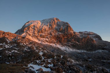 Mavi gökyüzüne karşı kayalık dağ manzarası.