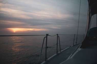 Gün batımında dalgalı denizde seyreden bir geminin yakın çekimi.