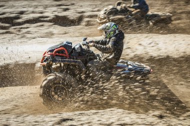 Yarış sırasında çamurlu bir pistte Can-Am Outlander 'a binen bir adamın yan görüntüsü.