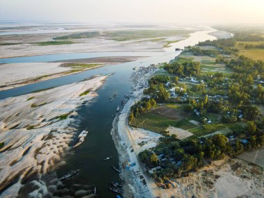 Bulutlu mavi gökyüzünün altında yeşilliklerle çevrili akan nehrin hava manzarası.