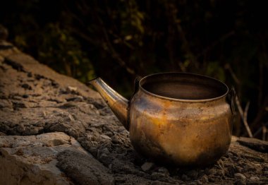 Bir kayanın üzerinde eski paslı bir çaydanlığın yakın çekimi.