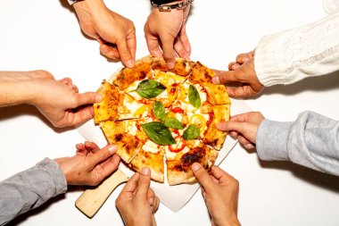 Tüm pizzadan dilimler alan ellerin üst görüntüsü.