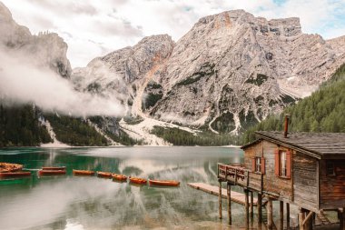 Arkasında karlı dağ olan ahşap bir ev manzarası.