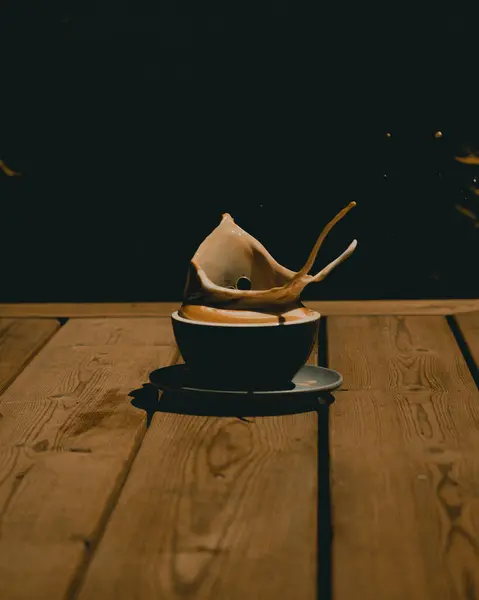 木製のテーブルの上に広がるコーヒーとカプチーノのマグカップの垂直クローズアップショット — ストック写真