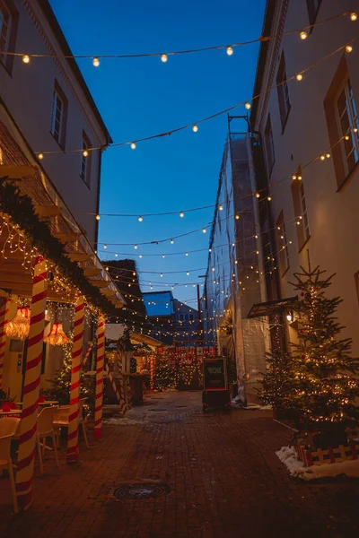 幻想的な光とクリスマスツリーで飾られた狭い通りの垂直方向の景色 — ストック写真