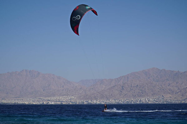 The wind surfing in the sea of Eilat, Israel with the city of Aqaba in Jordan in the background