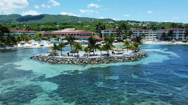 Jamaika 'nın Montego Körfezi' ndeki turkuaz denize karşı yeşillikle kaplı bir plajdaki otellerin antenleri.