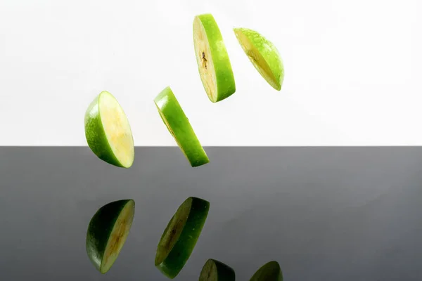 Плавающие Круглые Ломтики Зеленого Яблока Над Отражающей Поверхностью — стоковое фото