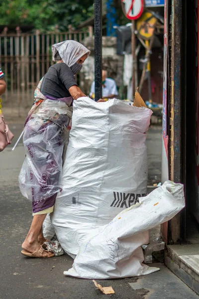 インドのムンバイでゴミ袋の中にプラスチックを見つける貧しい老婦人の垂直ショット — ストック写真