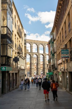 İspanya, Segovia sokaklarında bulutlu bir gökyüzünün altında gezinen turistlerin dikey görüntüsü