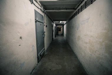 Eski beyaz duvarları ve demir-gri kapıları olan terk edilmiş bir binanın ürkütücü manzarası.