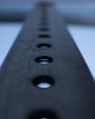 Bulanık arkaplanda delikleri olan metal bir yüzeyin dikey görüntüsü.