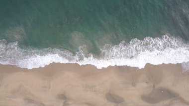 Güneşli bir günde dalgalı kumsal manzarası.