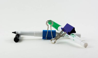 Beyaz arkaplanda izole edilmiş metal cilt ataçları ve işaretleyicilerin yakın plan çekimi