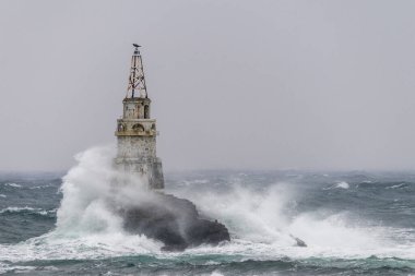 Bulgaristan 'ın Ahtopol kentindeki deniz fenerinin bulutsuz bir gökyüzüne karşı dalgalı bir deniz manzarası
