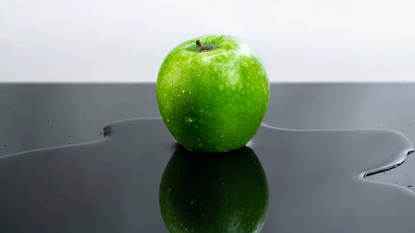 Uma Maçã Verde Fresca Uma Mesa Preta Com Água Derramada — Fotografia de Stock