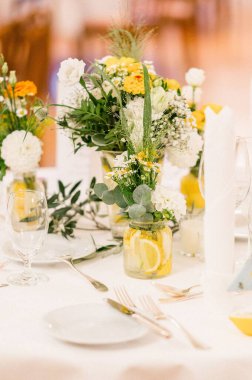 Düğün çiçekleriyle süslenmiş bir düğün masası resmi.